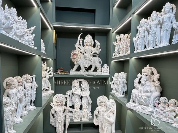 Showroom shelves lined with white marble moortis, with Durga Maa in the centre niche